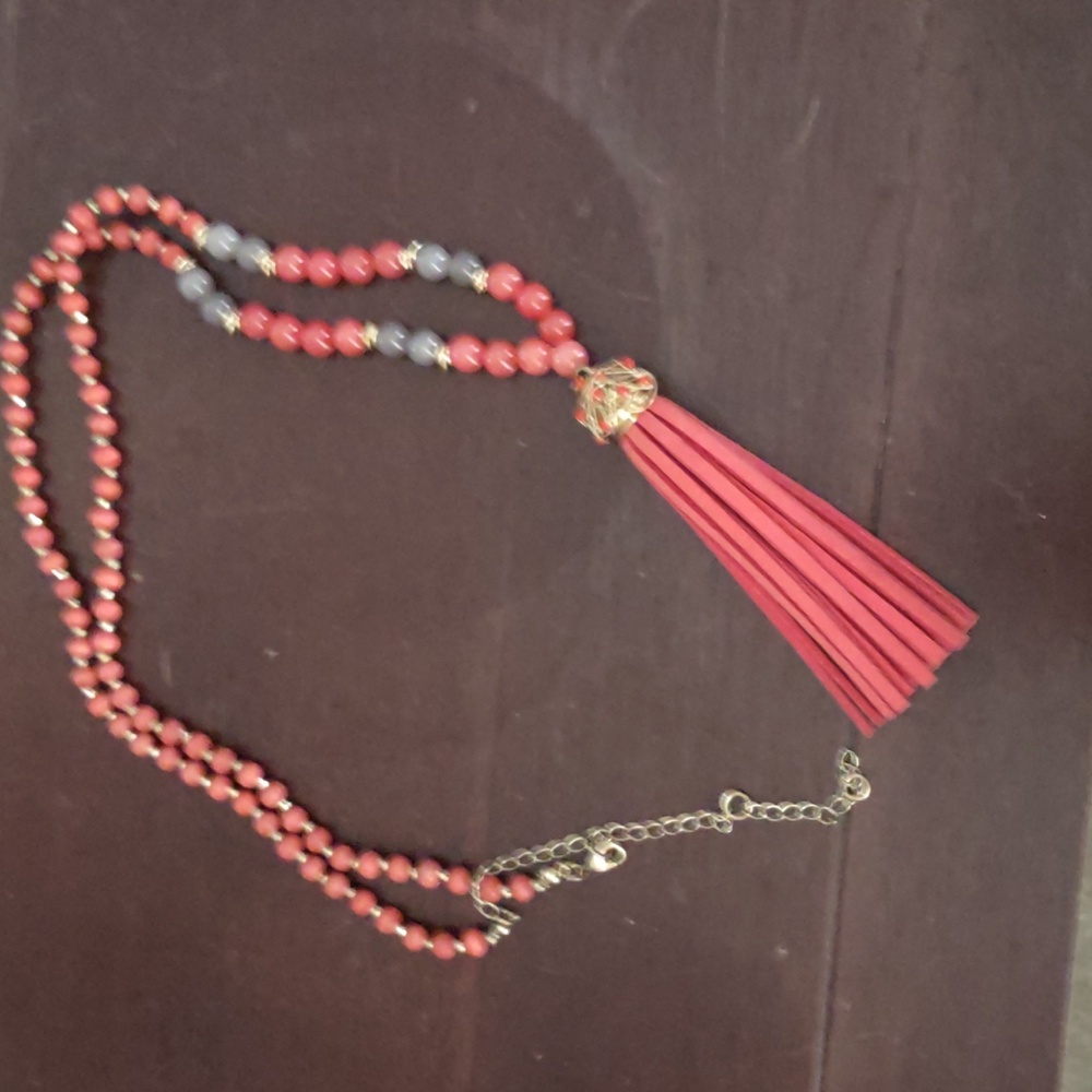 Long orange beaded necklace with a orange tassel and gold-tone accents.